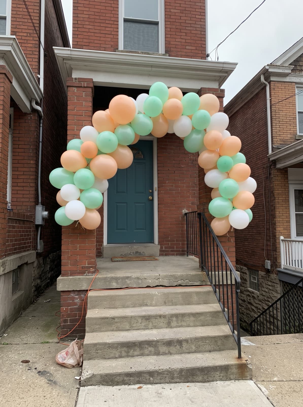 Balloon arch over a brick rowhouse door at the top of steep front steps